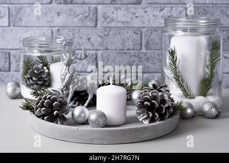 Concrete tray with candles, pine cones, fir branches and silver Christmas balls with a deer on a black background. Interior for christmas with candles Stock Photo
