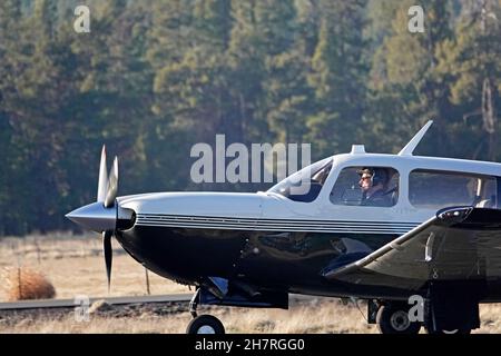 A Mooney M20M single engine aircraft, taking off at a small country airport in Sunriver, Oregon. Stock Photo