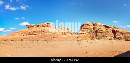 Rocky massifs on red sand desert, bright blue sky in background - typical scenery in Wadi Rum, Jordan Stock Photo