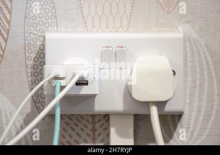 A plug and USB plugged into an electricity wall socket Stock Photo
