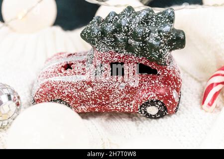Red car with Christmas tree on white sweater, led lights. Christmas decoration on the snow Stock Photo