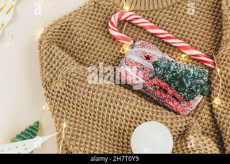 Brown knitted sweater and garlands, led lights. Women fashion winter clothes and accessories. New year and Christmas celebration mockup. Christmas bac Stock Photo