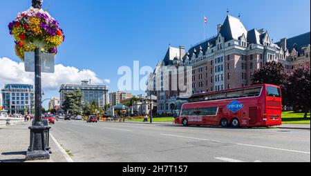 Photo of Fairmont Empress Hotel and red touristic bus on a street at Victoria Inner Harbor in Vancouver Island BC Canada Stock Photo