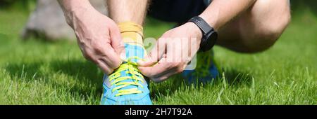 Man is tying laces on bright blue sneakers Stock Photo