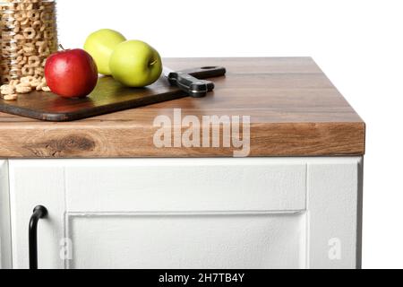 Apples with board and knife on kitchen counter against white background Stock Photo