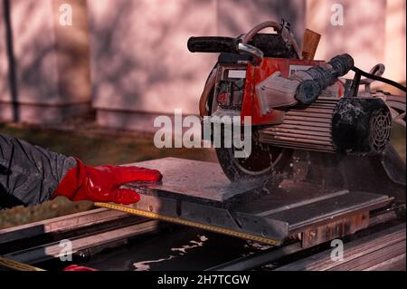 Man's hands using granite sawing machine Stock Photo