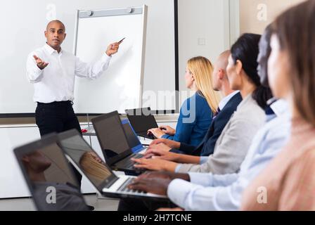 latino male instructor explained something to students in meeting room ...