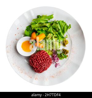 Tartar beef with quail egg and arugula served on plate. Modern French cuisine Stock Photo