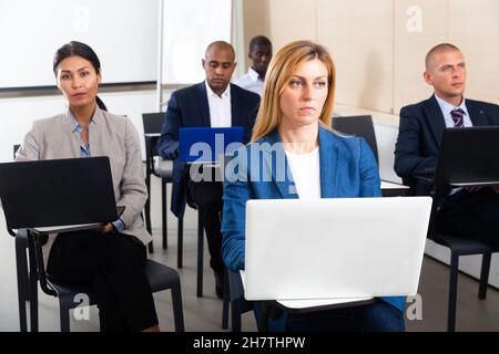 Concentrated businesspeople working on laptops during corporate seminar Stock Photo