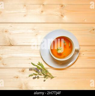 Herbal flower tea in a saucer cup on a warm wooden background. Stock Photo