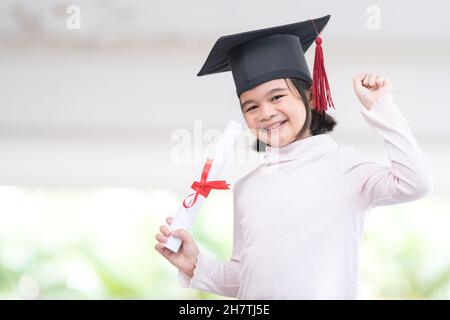 Happy Southeast Asian schoolgirl with a certificate celebrating graduation in Thailand Stock Photo