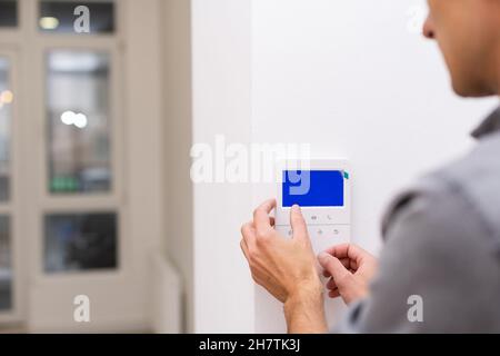 Man installing security alarm system on light wall at home, closeup Stock Photo