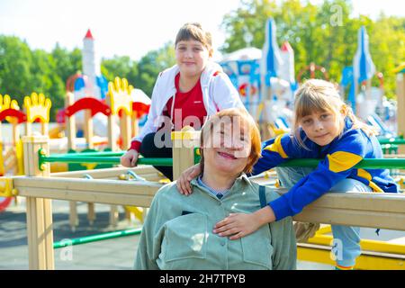 Grandmother walks with her grandchildren on playground Stock Photo