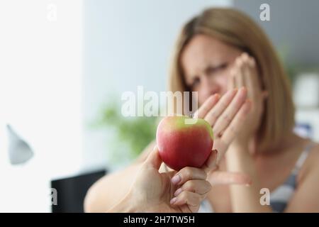 Blonde woman refuse to eat apple because of teeth pain Stock Photo