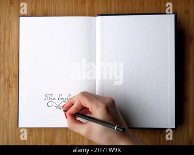 Girl hand writes on the last page of open sketchbook Stock Photo
