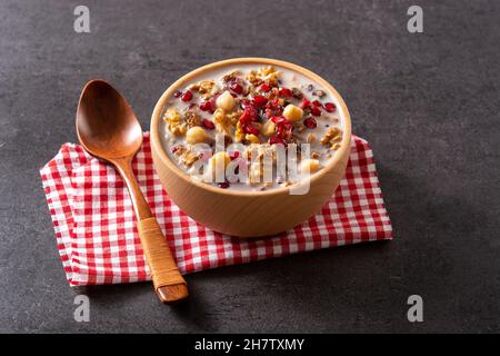 Traditional Turkish Noah's pudding in bowl on black slate background Stock Photo