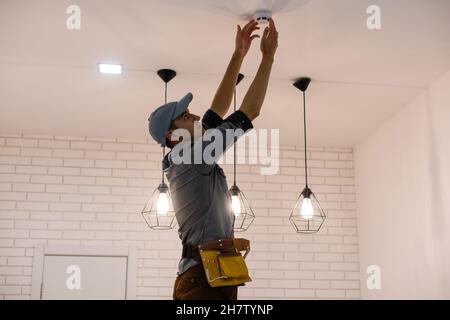 Handyman installing a smoke detector on the ceiling Stock Photo