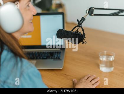 Woman recording podcast at table with mic Stock Photo