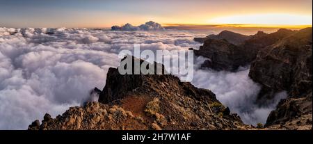 Panoramic sunset over the sea of clouds that covers the mountains of the Caldera de Taburiente in which the ash cloud expelled by the eruption of the Stock Photo