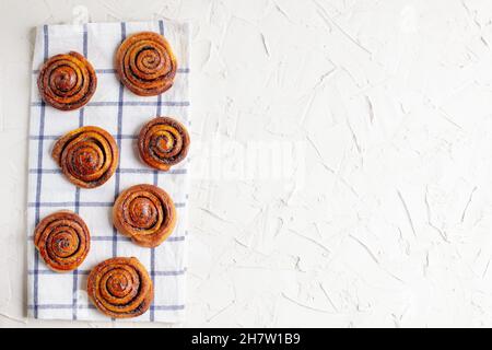 baked cinnamon buns on light background with checkered napkin. Top view Stock Photo