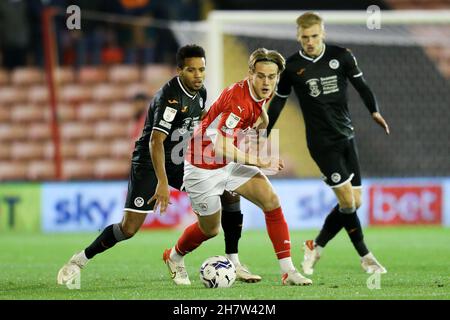 Barnsley, England, 24th November 2021.  Josh Benson of Barnsley (centre) and Ethan Laird of Swansea City (left) battle for the ball during the Sky Bet Championship match at Oakwell, Barnsley. Picture credit should read: Isaac Parkin / Sportimage Stock Photo