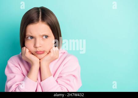 Photo of short hairdo sad little girl hands cheeks look empty space wear pink sportswear isolated on teal color background Stock Photo