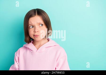 Photo of sad short hairdo little girl look empty space wear pink sportswear isolated on teal color background Stock Photo