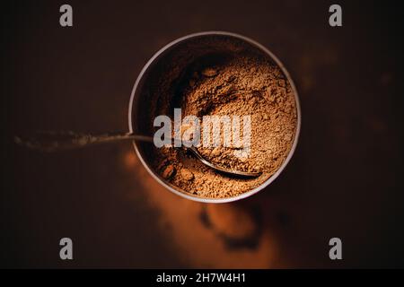 Top view of a jar filled with delicious aromatic natural cocoa powder, which contains a beautiful elegant teaspoon. A small jar of delicious drink in Stock Photo