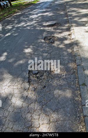 Three big holes on the asphalt road that are very dangerous when it rains. Then it is impossible to spot them from the car. Stock Photo