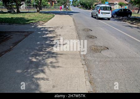 Three big holes on the asphalt road that are very dangerous when it rains. Then it is impossible to spot them from the car. Stock Photo