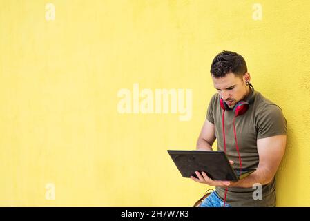Portrait of an excited man holding laptop computer isolated on yellow background, Feeling happiness, Hispanic Male model Stock Photo
