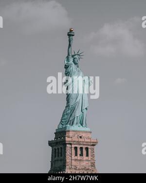 Vertical shot of the Statue of Liberty standing at Liberty Island at Hudson River in New York, Stock Photo