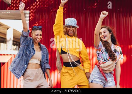 Female friends dancing and having fun. Three energetic young friends having a good time together outdoors. Group of multiethnic generation z friends m Stock Photo