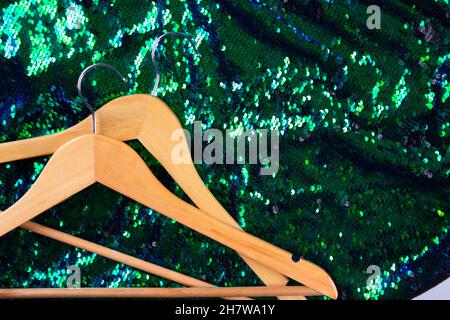 Hangers on green fashion sequins fabric background with copyspace. Conscious and environmentally friendly consupmtion - clothing rental service. Slow Stock Photo