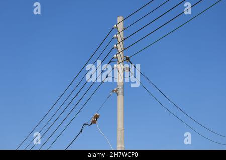 Five electrical cables on pole in Malta - blue sky background - Three-phase electric power Stock Photo