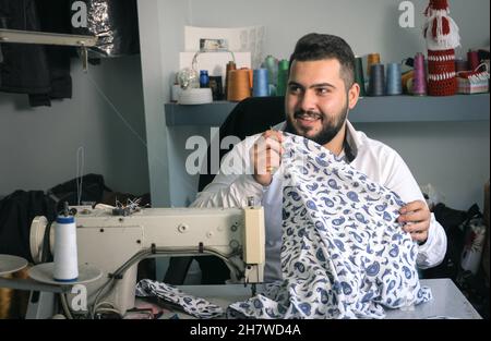 Happy Middle Eastern young man working at his tailor shop. Small business or self-employed concept Stock Photo