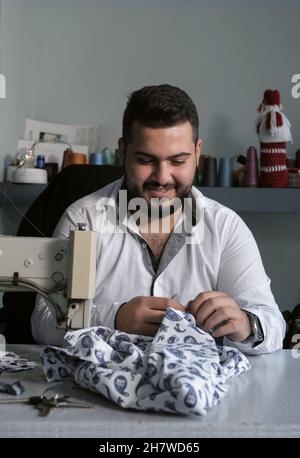 Middle Eastern young man working at his tailor shop. Small business or self-employed concept Stock Photo