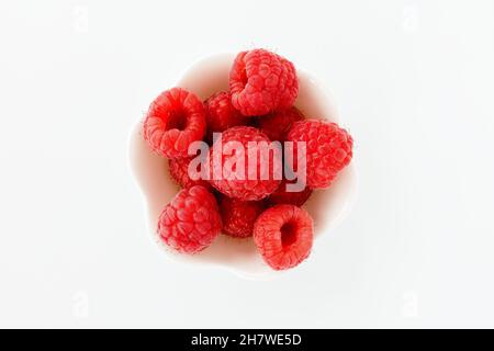 Closeup of fresh raspberries in a cute white bowl isolated on white background. Top view. Stock Photo