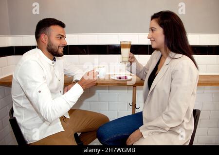 Couple having coffee. Couple in coffee shop. Boy and girl with coffees. Appointment. Work break. Relaxed man and woman having coffee. Stock Photo