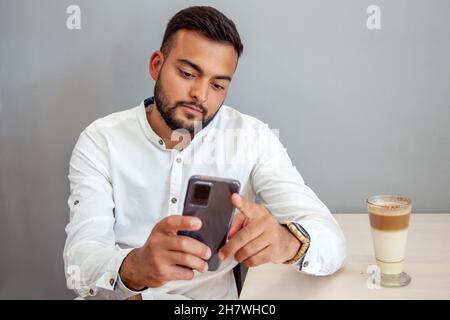 Man with a mobile. Man looking at mobile. Man in coffee shop with mobile. Man having coffee at cafe. Stock Photo