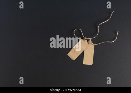 On a dark background, two blank trade labels, price tags from kraft paper with rope. Mockup, advertising flyer. Place for your text. Horizontal photo. Stock Photo