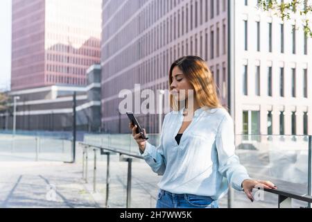 Business latin woman is having a business discussion through the phone surrounded by buildings. Business concept Stock Photo