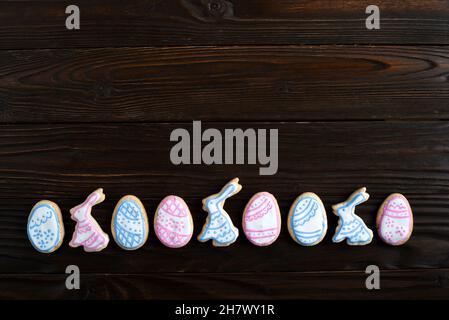 Easter frosted cookies in shape of egg and rabbit on dark wooden background. Flat lay with copy space. Stock Photo