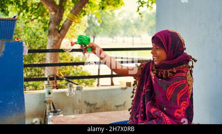Kid plays with soap bubble’s gun outdoor. Asian Little Indian Girl Shooting Bubbles from Bubble Blower outside the house. Stock Photo
