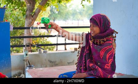 Indian little girl in the backyard is playing with a Bubble gun. Cute girl in summer playing with water and soap bubbles close-up and copy space. Stock Photo