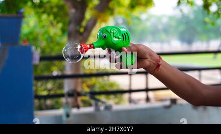 Unidentified kids holding a soap bubble blower gun. Kids with bubble blower. Stock Photo