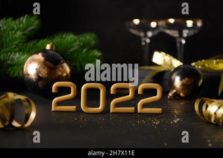 New Year estive composition with number of year , gift, baubles, gift and wine glasses, Christmas decorations on black background. Close up. Holiday g Stock Photo