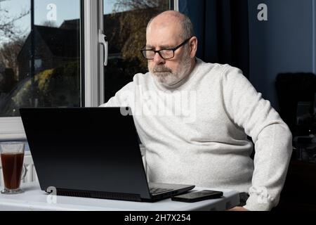 man working on a laptop from a home office. Stock Photo