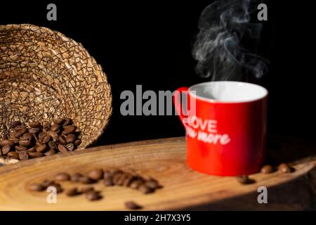 Red coffee cup on wooden table, coffee grains, black background Stock Photo