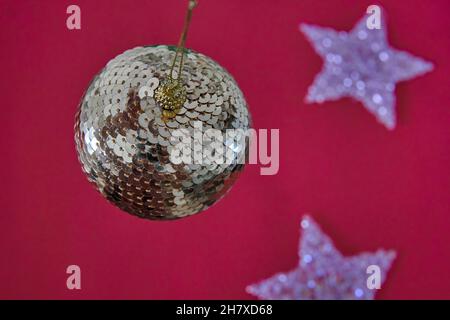 Gold glitter shiny christmas ball hanging on red background and shiny stars. Horizontal Stock Photo
